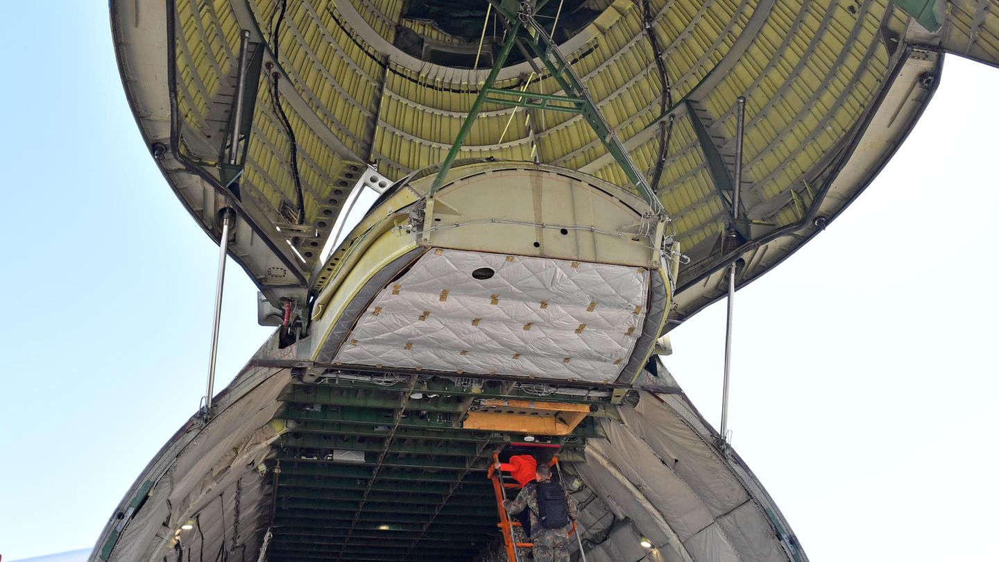 Die geöffnete Bugklappe von unten: Auf der Leiter klettert eine Dame in roter Jacke aufwärts...