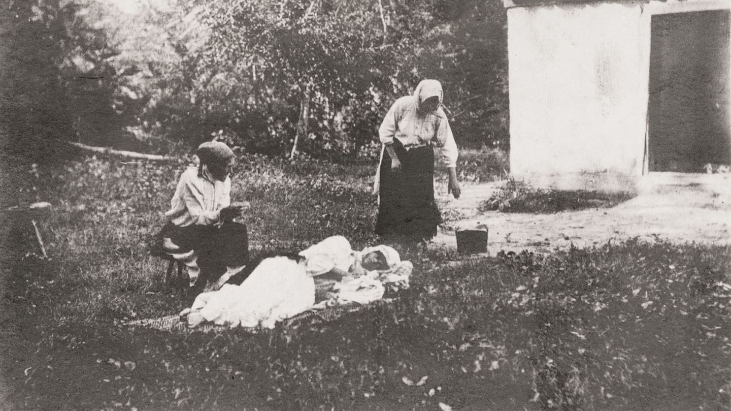Eine Grippekranke wird von zwei Frauen umsorgt. Diese seltene Ansichtskarte entstand um 1918.