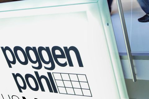 Ein Mitarbeiter der Poggenpohl Möbelwerke in Herford geht im Ausstellungsraum hinter einem Firmenschild an einer Küche vorbei