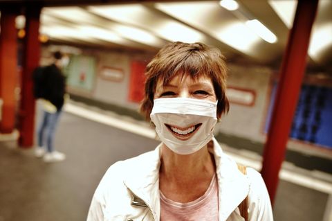 Passantin mit Mund-Nasenschutz blickt an der Berliner U-Bahnhaltestelle Alexanderplatz in die Kamera