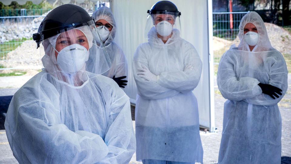 Vier Personen mit Schutzkleidung und verschränkten Armen