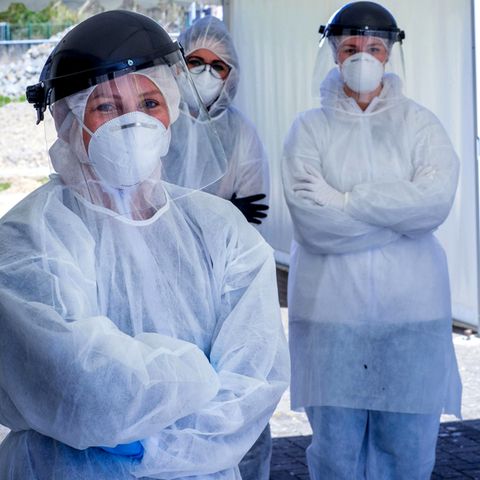 Vier Personen mit Schutzkleidung und verschränkten Armen