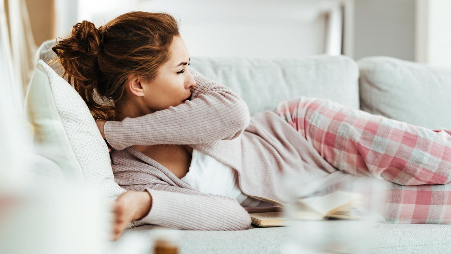 Impfung Pneumokokken: Eine Frau liegt auf dem Sofa und hustet