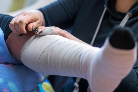 Eine Frau legt einer zu pflegende Person einen Thrombose-Verband an