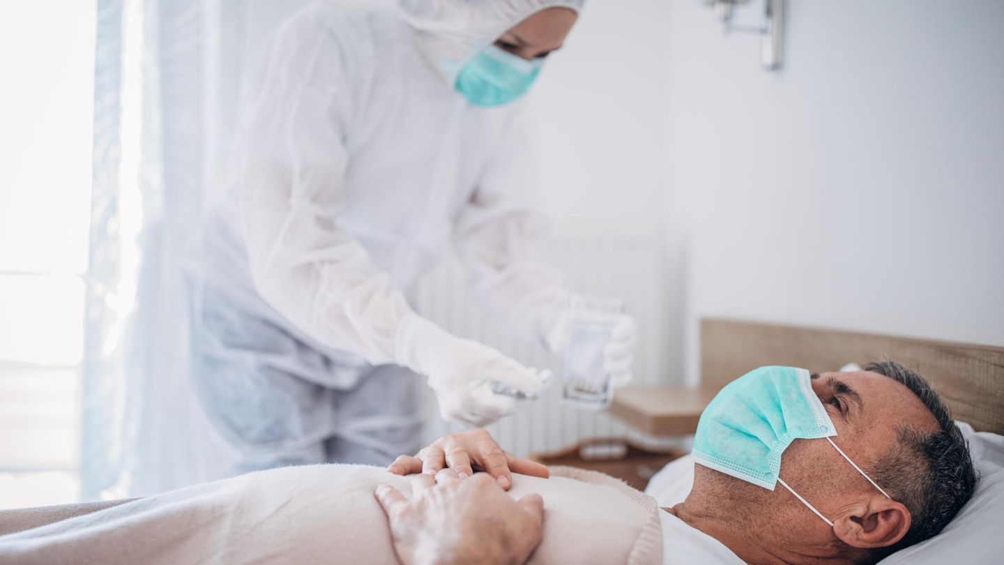 Ärztin untersucht einen Patienten in Schutzkleidung Ärztin untersucht einen Patienten in Schutzkleidung
