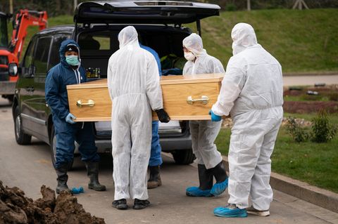 Sargträger in Schutzanzügen bringen im britischen Chislehurst einen Sarg zu einem Leichenwagen
