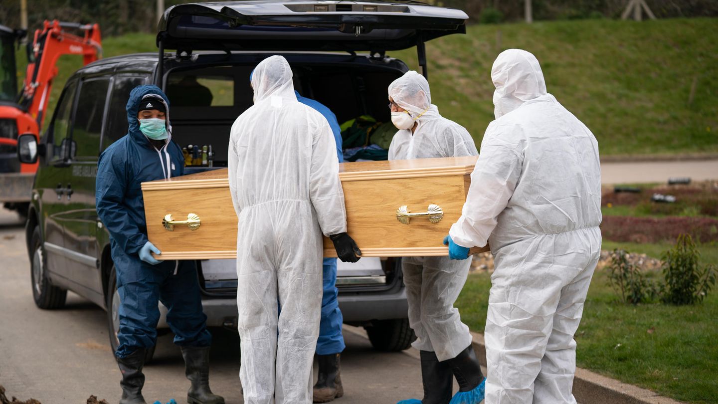 Sargträger in Schutzanzügen bringen im britischen Chislehurst einen Sarg zu einem Leichenwagen
