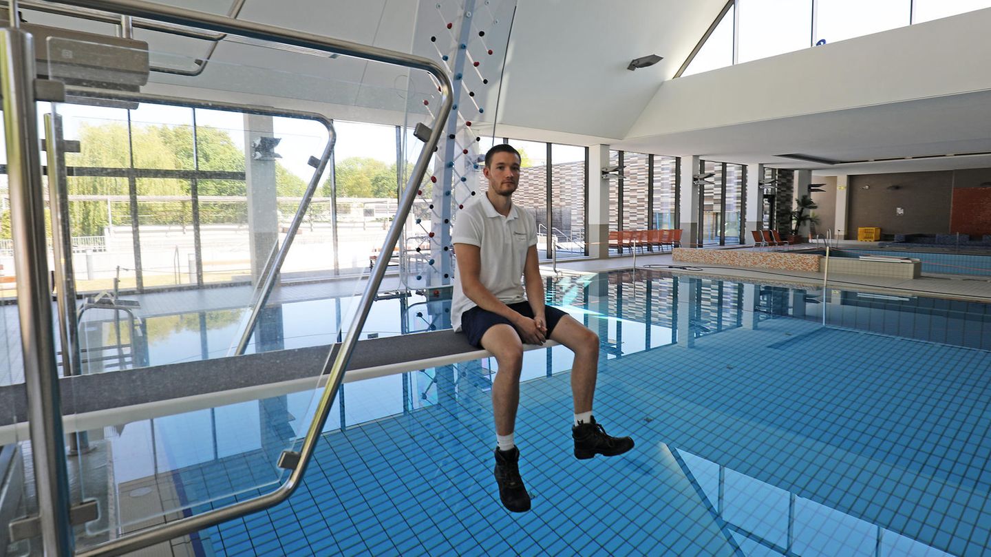 Thomas Dyck, Schwimmmeister, sitzt im leeren Zollstockbad in Köln auf einem Sprungbrett