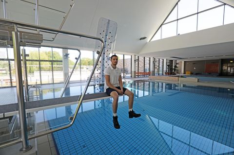 Thomas Dyck, Schwimmmeister, sitzt im leeren Zollstockbad in Köln auf einem Sprungbrett