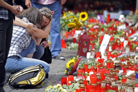 Kerzen, die die Trauer nicht mildern: Zwei Frauen am Unglücksort kurz nach der Katastrophe im Juli 2010