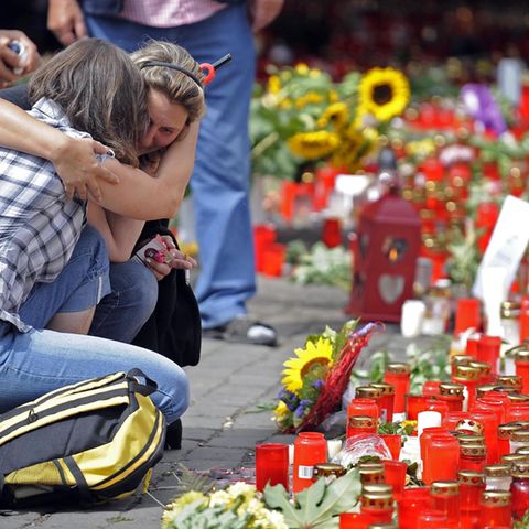 Kerzen, die die Trauer nicht mildern: Zwei Frauen am Unglücksort kurz nach der Katastrophe im Juli 2010