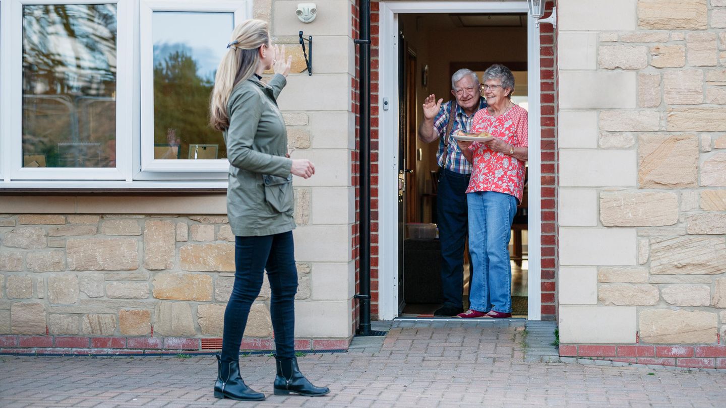 Altes Ehepaar winkt aus der Haustür einer jungen Frau