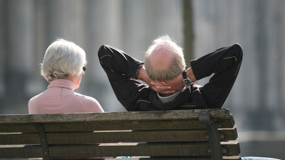 Ein älterer Mann und eine ältere Frau sitzen auf einer Bank, von hinten fotografiert Ein älterer Mann und eine ältere Frau sitzen auf einer Bank, von hinten fotografiert