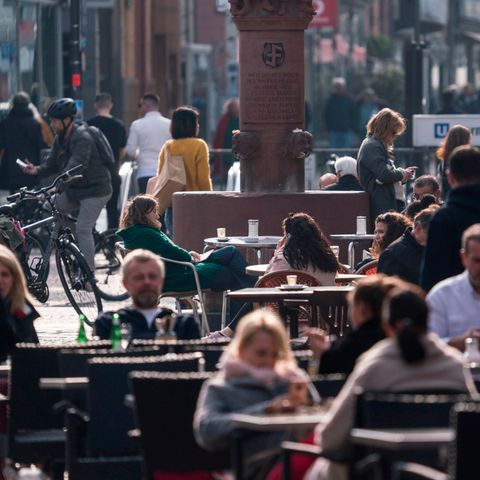 Menschen sitzen an der Berger Straße in Frankfurt noch in den Straßencafes