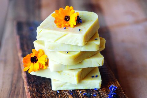 Seifenblöcke gestapelt auf Holzbrett mit gelben Blüten