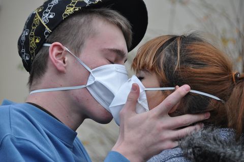 Junges Paar küsst sich mit Masken