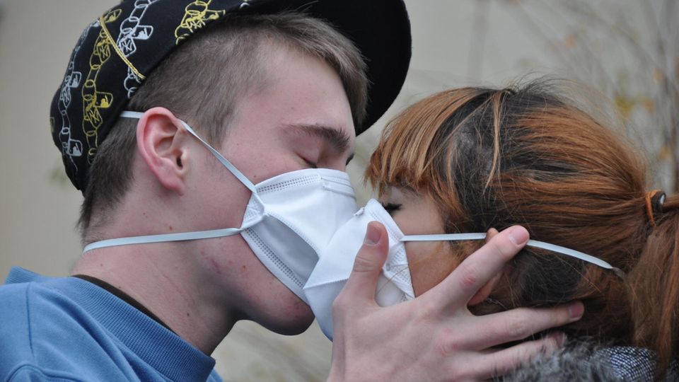 Junges Paar küsst sich mit Masken