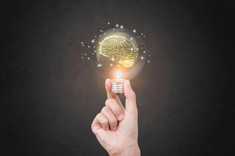 Ein Hand hält eine Glühbirne in der ein Hirn leuchtet