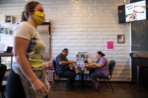 Servicekraft mit Maske und Gäste im Restaurant
