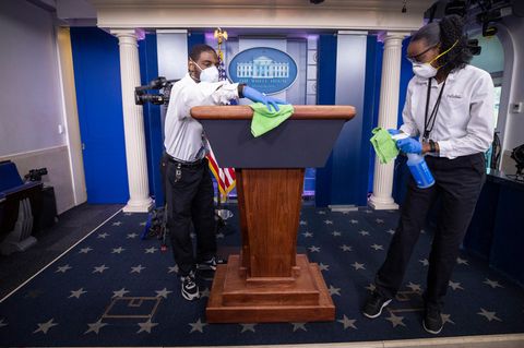 Ein Reinigungsteam wischt das Rednerpult ab, bevor US-Präsident Trump spricht