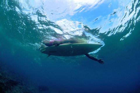 Ein Surfer paddelt im Wasser