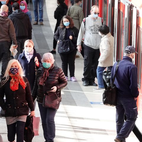 Mit Mundschutz sind Fahrgäste am Hamburger Hauptbahnhof auf einem Bahnsteig unterwegs