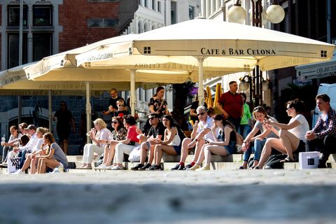 Zahlreiche Menschen sitzen in der Innenstadt von Oldenburg auf den Treppen am Rathausmarkt, wo sonst die Tische und Stühle der Gastronomie unter Schirmen stehen