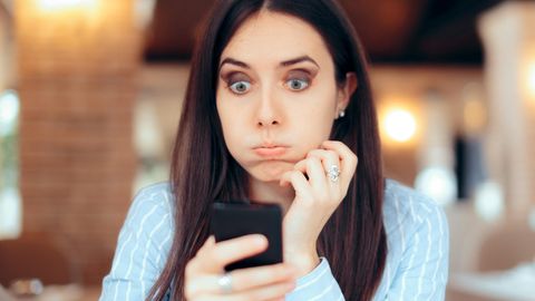 Frau schaut genervt auf ihr Smartphone