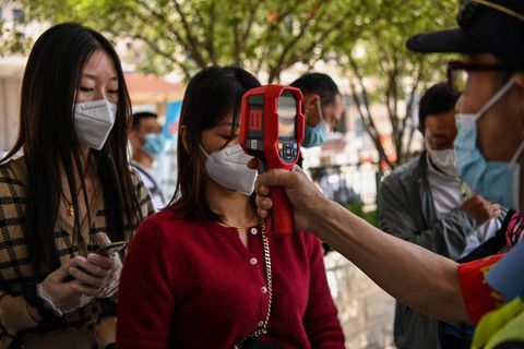 Bei einer Frau in Wuhan wird die Temperatur gemessen