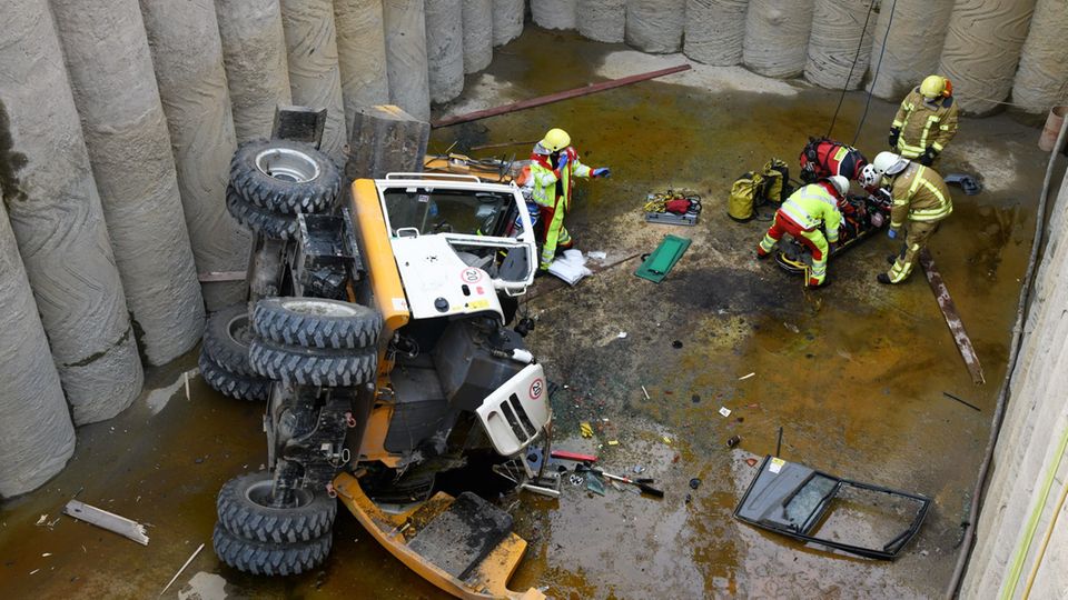 Nachrichten aus Deutschland: Baggerführer fällt in acht Meter tiefe Grube Sanitäter und Feuerwehrleute bereiten einen verletzten Baggerfahrer auf seine Bergung vor