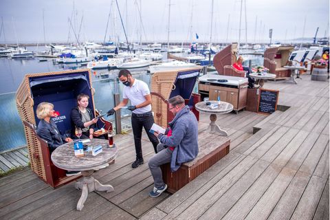 Mecklenburg-Vorpommern, Kühlungsborn: Ein Kellner bringt einer Familie die Speisekarten