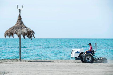 Ein Mann auf einem Fahrzeug bereitet einen Strand auf die Wiederöffnung im Sommer vor