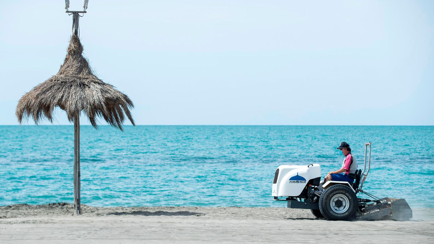 Ein Mann auf einem Fahrzeug bereitet einen Strand auf die Wiederöffnung im Sommer vor