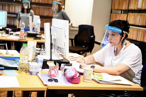 Frau vor Computer mit Schutzschirm vor dem Gesicht