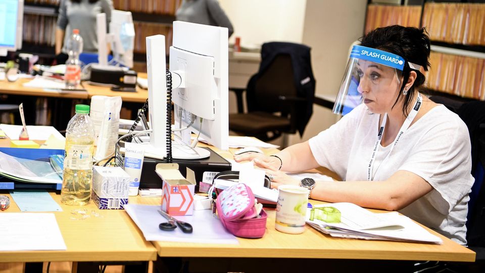 Frau vor Computer mit Schutzschirm vor dem Gesicht