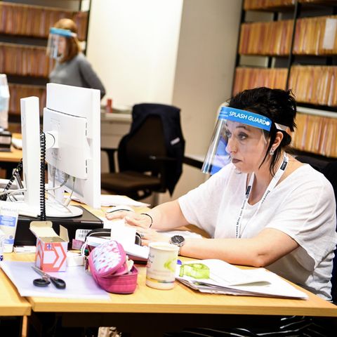 Frau vor Computer mit Schutzschirm vor dem Gesicht