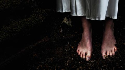 Füße auf dunklem Waldboden