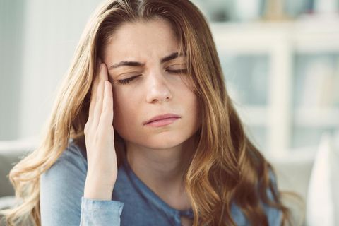 Eine Frau hält sich vor Schmerzen die Schläfe