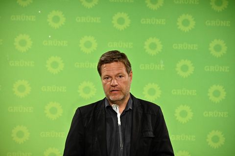 Robert Habeck spricht vor einer grünen Wand