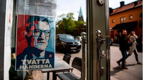 Ein Schild mit einem Porträt von Anders Tegnell hängt am Eingang eines Restaurants in Stockholm