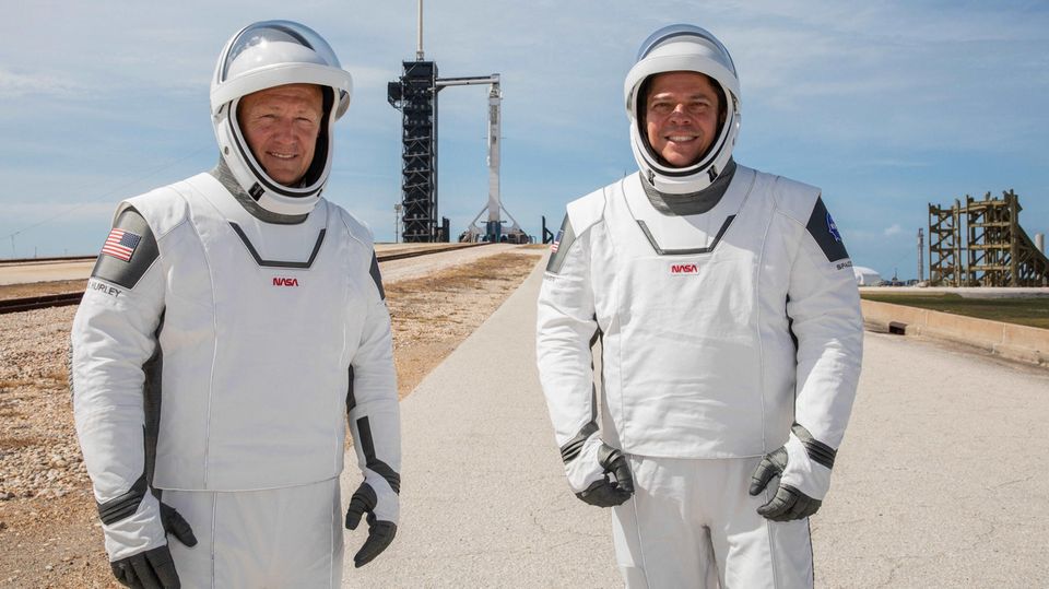 US-Astronauten Douglas Hurley und Robert Behnken mit Falcon-9-Rakete im Hintergrund