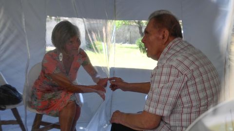 Ein Ehepaar im Bubble Tent, sie hält durch die Folie seine Hand