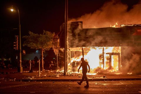 Ein Mann steht in der Nacht vor einem brennenden Gebäude