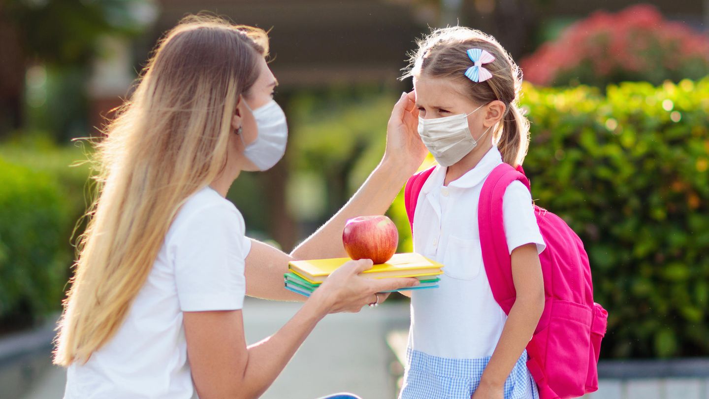 Schulkind und Mutter mit Mundschutzen