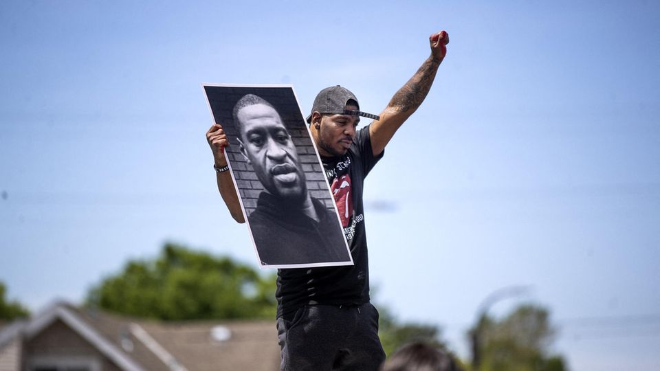 Demonstrant hält in Minneapolis  einen Zettel mit dem Porträt von George Floyd in die Höhe