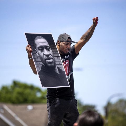 Demonstrant hält in Minneapolis  einen Zettel mit dem Porträt von George Floyd in die Höhe