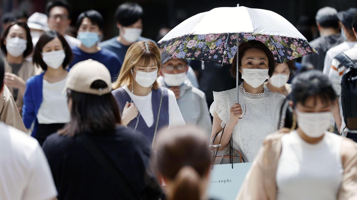 Zahlreiche Passanten mit Mundschutz gehen in Osaka, Japan auf einer Straße