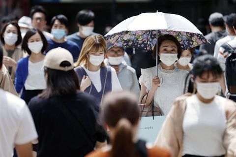 Zahlreiche Passanten mit Mundschutz gehen in Osaka, Japan auf einer Straße