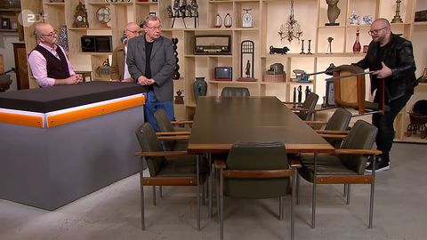 "Bares für Rares"-Experte Sven Deutschmanek wuchtet die Möbel von Ulrich Wiechoczek und Wolfgang Hoffmeister in die Höhe, Moderator Horst Lichter schaut zu.