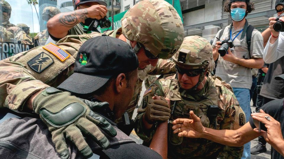 Soldaten gehen mit Demonstranten auf die Knie